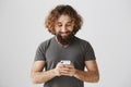 Best way of communication. Portrait of pleased and concentrated eastern male holding smartphone, playing games or