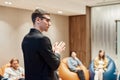 The best way to learn. Young male speaker in suit giving a talk at informal business meeting in modern workspace