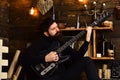 Best weekend. Man with beard holds black electric guitar. Man bearded musician enjoy evening with bass guitar, wooden Royalty Free Stock Photo