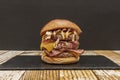 Bestial three-meat burger with lots of fried bacon, cheddar cheese Royalty Free Stock Photo