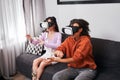 Besties sitting at the sofa and using virtual reality headset