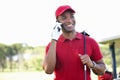 Bet you wish you were here. a young man standing on a golf course and talking on his cellphone.