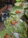 Betel leaves or mitha paan being prepared with ingredients like areka nut or supari and other condiments in a shop for sale in