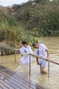 Pilgrims from different countries accept the rite of baptism in the Jordan River in Israel