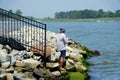 A man fishing by the rocks on the bay near Bethany Beach, Delaware