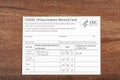 Close up isolated image of a COVID 19 vaccination record card on a wooden desk Royalty Free Stock Photo