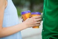 Betrothed couple with coffee cups in hands, walking in park.