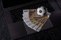 Bets, sports betting, bookmaker. Soccer ball and money on a laptop`s keyboard Royalty Free Stock Photo