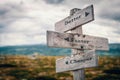 Better, faster, cheaper text on wooden sign post outdoors in landscape scenery.