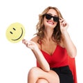 Betting on happiness. A charismatic young woman wearing glasses and holding a paddle with a smiley face on it. Royalty Free Stock Photo