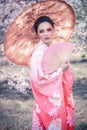 Beuatiful girl with japanese traditional kimono and umbrella in orchard during spring