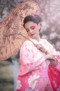 Beuatiful girl wearing japanese traditional kimono in orchard during spring