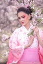 Beuatiful girl wearing japanese traditional kimono in peach orchard during spring