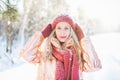 Beutiful blonde female with green eyes with snowflakes on her hair and red hat on a winter day