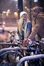 Beutiful blonde with long hair looking her boyfriend, laughing about riding bicycles while snowing. christmastime concept