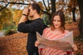 Beutiful couple travelling together. She holds map and study it. He look in binoculars in one direction. Woman pose.