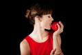 Beutiful woman in red dress licking an apple