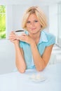 Beutiful young woman sitting at table holding cup of coffee and