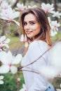 Beuty portrait of young girl near blossom magnolia flowers outdoors in spring park