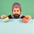 Beverages and cozy season time. Man in warm hat holds orange and green cups