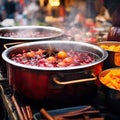 Beverages fruits and berries hot mulled wine in pots. Traditional Christmas food in cauldron and pot on fire background.