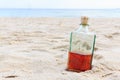 Beverrage alcohol is brandy bottle on sand beach.