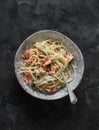 Bevette creamy pasta with baked trout on a dark background, top view