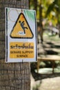 A beware slippery surface sign placed on tree Royalty Free Stock Photo