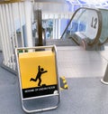 Beware uneven floor warning sign on yellow board in front of escalator in shopping mall. Beware uneven floor warning sign for Royalty Free Stock Photo