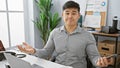 A bewildered asian man gestures confusion in a modern office setting, amid technology and business decor Royalty Free Stock Photo
