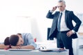 Bewildered chief looking at his employee sleeping at work Royalty Free Stock Photo