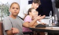 Confused preteen girl sitting at computer table in training room