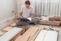 Bewildered man assembling new wooden furniture at home. Man reading instructions and misunderstand what to do the next.