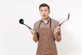 Bewildered man chef or waiter in striped brown apron, shirt holding black ladle or kitchen spoon, spatula isolated on