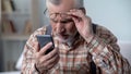 Bewildered old man looking at cellphone, new technology complicated for elderly