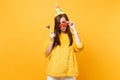 Bewildered puzzled woman in birthday hat holding orange funny glasses with playing pipe standing celebrating isolated on