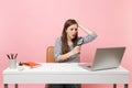 Bewildered woman clinging to head looking through magnifying glass on pc laptop while sit work on project at office Royalty Free Stock Photo