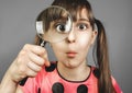 Bewilderment child girl looking through magnifying glass