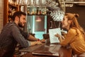 Bewitching woman discussing a menu with handsome dark-haired bearded bartender