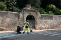 Portrait of municipal employee sweeping the street in front of an urban park