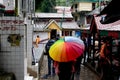 Young indian girl with a colorful umbrella in a busy market place street in McLeodganj