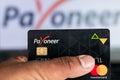 Bhairahawa, Nepal - June 27 2020: Man holds Payoneer Prepaid MasterCard against laptop computer. Payoneer funds were recently put