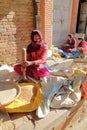 BHAKTAPUR, NEPAL - DECEMBER 29, 2014: A young woman pounding the grain outside her home in the street