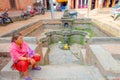 BHAKTAPUR, NEPAL - NOVEMBER 04, 2017: Unidentified woman sitting in a plaza close to a empty fountain view of ancient Royalty Free Stock Photo