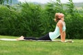 Bhujangasana cobra pose by woman on green grass in the park Royalty Free Stock Photo