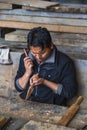 Bhutanese artisan carving a wooden vajra with knife , Bhutan