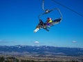 Chairlift on blue sky with a snowboarder and skiers