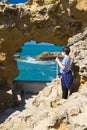 Biarritz, France - May 20, 2017: young boy looking through sea cave hole admiring beautiful view on atlantic ocean with waves in b