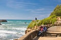 Biarritz, France - May 20, 2017: Young couple admiring beauty of seascape on atlantic coast in springtime with blooming trees in b