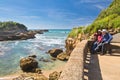 Biarritz, France - May 20, 2017: Young couple admiring beauty of seascape on atlantic coast in springtime with blooming trees in b